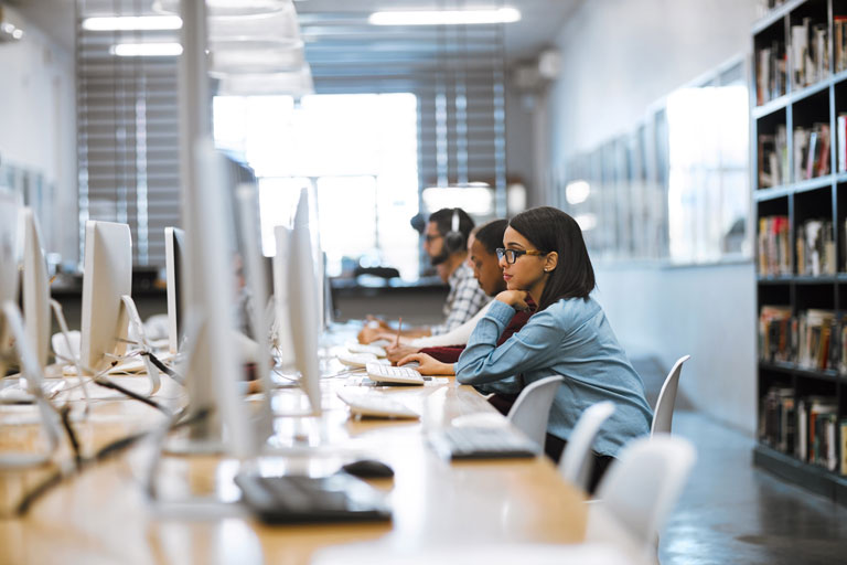 Universitätsstudenten, die in der Bibliothek auf Computern arbeiten